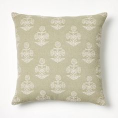 a green and white pillow on a white wall with a plant pattern in the middle