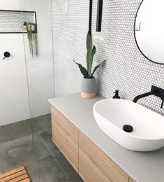 a white sink sitting next to a wooden counter top under a mirror in a bathroom