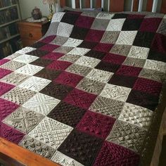 a bed with a large quilt on it in a room next to a book shelf