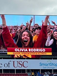 a large group of people in front of a screen at a sporting event with their hands up