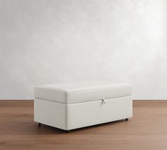 a white storage box sitting on top of a wooden floor in front of a wall