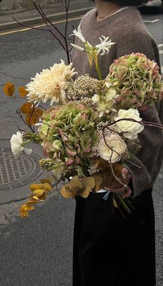 a woman holding a bouquet of flowers on the street