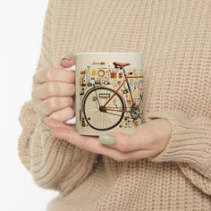 a woman is holding a coffee mug with a bicycle on the front and side, in her hands