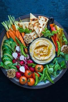 an assortment of vegetables and pita bread on a plate with utensils in the middle