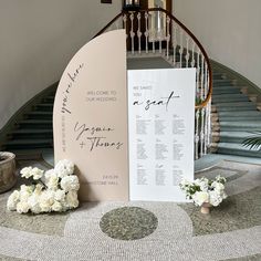 the welcome sign is next to some flowers on the table in front of the stairs