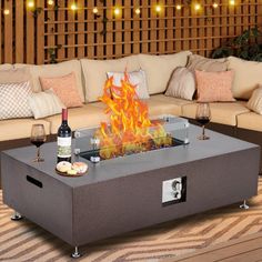 a fire pit sitting on top of a wooden floor next to couches and pillows