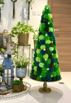 a green and blue christmas tree sitting on top of a table next to other decorations