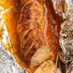 meat wrapped in tin foil with sauce and herbs on the top, ready to be cooked