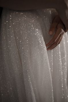 a woman's hand on the back of a white dress with sparkling sequins