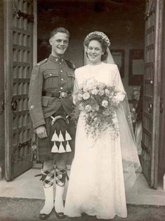 an old black and white photo of a bride and groom standing in front of a door