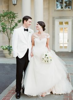 a bride and groom smile at each other while standing in front of an old building