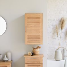 a white toilet sitting next to a wooden cabinet in a bathroom under a round mirror