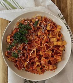 a white bowl filled with pasta covered in sauce and parmesan cheese