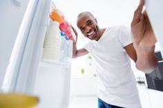 a man standing in front of a refrigerator with food on the door and smiling at the camera