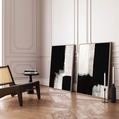 two black and white paintings are on the wall next to a chair in an empty room