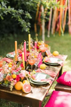 an outdoor table set up with plates, glasses and candles for a party or celebration