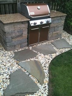 an outdoor grill with stone pavers around it