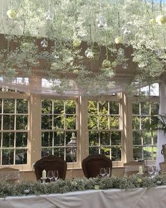 the table is set for an event with flowers and greenery hanging from the ceiling