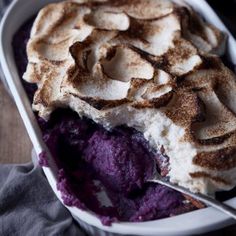 a dish filled with purple ice cream and topped with cinnamon swirl on the top, next to a spoon