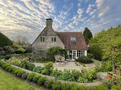 a house surrounded by lush green plants and flowers on a sunny day with blue sky in the background