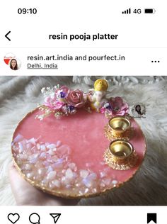 a person holding a pink and gold tray with flowers on it in front of a white rug