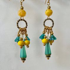 A sunny pair of earrings!  Golden rings hold faceted turquoise glass drops, yellow faceted glass beads and turquoise-colored flowers set off with small gold-plated beads. Larger faceted yellow glass beads hold each ring, and are topped with a small plated bead.  Total earring length is 3 inches. Yellow And Teal Clothing Accessories, Bohemian Gold Faceted Earrings, Yellow Beaded Czech Glass Earrings, Yellow Beaded Earrings With Czech Glass, Yellow Beaded Earrings In Czech Glass, Nickel-free Yellow Dangle Beaded Earrings, Nickel Free Yellow Dangle Beaded Earrings, Bohemian Gold Earrings With Faceted Beads, Yellow Teardrop Earrings With Dangling Beads