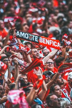 a large group of people holding up signs in the air and wearing red shirts with white letters on them