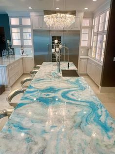 a marble counter top in a kitchen with white cabinets and chandelier hanging from the ceiling