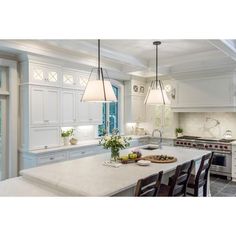 a large kitchen with white cabinets and an island in front of the stove top oven