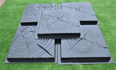 four pieces of black plastic sitting on top of green artificial grass in the shape of squares