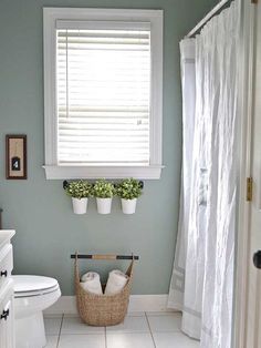 a white toilet sitting next to a window in a bathroom