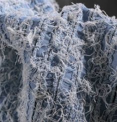 closeup of blue and white fabric with fraying on the edges, worn out