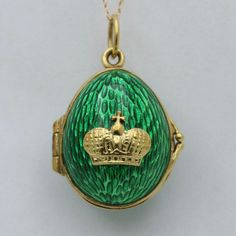 A beautifully constructed egg pendant modeled in rich 18K gold encased in a vibrant green enamel. Nestled on the front is a crown motif, a symbol of regality and grace. This locket opens, revealing a hidden space for your special keepsakes.  The interior of the locket is stamped "V.S. 18K" for gold purity.   Metal: 18K Yellow Gold Weight: 8.6 grams Measurements: 0.75 inch long (additional 0.4 inch bail) by 0.75 inch wide at its widest point Markings: "V.S 18K " Condition: In very good vintage condition with some minor surface wear.  Please note the chain in the photos is NOT included with this listing. Follow us on Instagram @alphaomegajewelry for the latest updates from our shop!  We have lots of fun there and add videos, highlights, and showcase our newest acquisitions. Formal Green Enamel Jewelry, Luxury Green Enamel Jewelry, Luxury Enamel Oval Pendant Jewelry, Luxury Oval Pendant Enamel Jewelry, Luxury Green Collectible Jewelry, Formal Green Locket Jewelry, Luxury Engraved Green Jewelry, Luxury Green Engraved Jewelry, Antique Jewelry Necklace