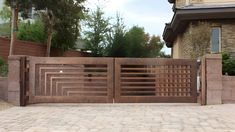 a wooden gate is shown in front of a brick wall and stone walkway with trees on the other side