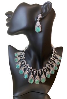 This CZ American Diamond Necklace is the perfect accessory for any outfit and any occasion. Its high-quality CZ American Diamond stones add a touch of elegance to any look, whether it's a silk saree, gown, lehanga, or more. The mint colorstone also adds a pop of color to your ensemble. Upgrade your jewelry collection with this versatile and beautiful necklace. This jewellery set includes a necklace and matching earrings. Jewellery Care- Keep the jewellery dry, avoid contact with perfumes and water. Elegant Party Jewelry Sets With Stone Setting, Hand Set American Diamond Necklace For Party, Elegant Crystal Jewelry Sets With Stone Setting, Luxury American Diamond Jewelry Sets For Party, Formal Festive Kundan Necklace With Stone Setting, Festive Formal Kundan Necklace With Stone Setting, Elegant Silver Kundan Necklace With Stone Work, Elegant Silver Jewelry With Stone Work, Elegant Kundan Necklace With Stone Work For Celebration