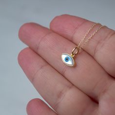 Εxtra tiny 14k solid gold evil eye pendant.  The pendant measures 11mm / 0.4 inches The evil eye pendant is available in 14k yellow gold with a white evil eye.  The  eye is made of mother of pearl (mop). The backside is closed, smooth 14k solid gold. Available with a solid 14k gold chain or as pendant only. Chains are available in 3 lengths, 16inches/40cm, 18inches/45cm and 20 inches/50cm Perfect gift for Valentine or any other special occasion. Comes in a gift box. 14k Yellow Gold Evil Eye Jewelry, 14k Yellow Gold Jewelry With Evil Eye, Fine Jewelry Featuring Evil Eye, Symbolic Evil Eye Jewelry, Everyday Yellow Gold Evil Eye Charm Necklaces, Everyday Yellow Gold Evil Eye Jewelry, Dainty Yellow Gold Evil Eye Charm Necklace, White 14k Gold Round Charm Necklaces, White 14k Gold Round Charm Necklace