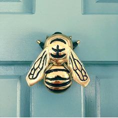 a close up of a metal door handle on a blue door with a bee design