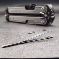 two pairs of swiss army knifes on top of a table next to some screwdrivers