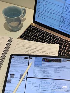 an open laptop computer sitting on top of a desk next to a notebook and pen