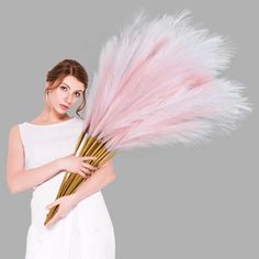 a woman holding a bunch of pink feathers