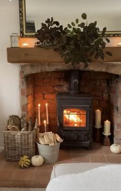 a living room with a fire place next to a basket filled with books and candles