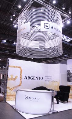 an exhibit booth with chairs and signs on the wall, suspended from the ceiling above it