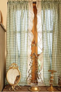 there is a window with green gingham curtains and a mirror next to it