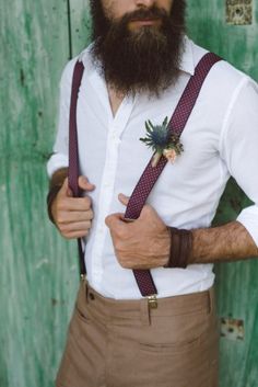 a man with a long beard wearing suspenders and a flower in his lapel