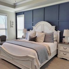 a large white bed sitting in a bedroom next to two lamps on either side of the bed