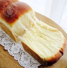 a loaf of bread sitting on top of a doily next to a slice of bread