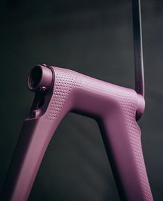 a close up of a purple bike frame on a black background with the handlebars extended