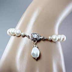 An elegant bridal necklace featuring freshwater pearls in an iridescent ivory color accented by a front-closing clasp adorned with clear cubic zirconia for added sparkle. A drop pendant of crystal and pearl adds class and dimension to the overall design. Versatile, the center ring and pendant can be removed and the necklace can be also worn as a classic strand of pearls with the clasp in the back. Two different necklaces in one. Necklace: 18" long (approx. 46cm) plus 2" for the drop pendant Earrings: 2" (approx. 5cm) long. Bracelet: 7.5" (approx. 19cm) long, with a delicate box clasp and pearl drop. Handcrafted - One of a kind design. Adjustable Classic Pearl Necklace For Wedding, Elegant Adjustable Bridal Necklace With Pearl Charm, Adjustable Pearl Drop Bridal Necklace For Formal Events, Single Strand Crystal Jewelry For Wedding, Elegant Single Strand Pearl Bracelet For Wedding, Classic Teardrop Jewelry For Mother Of The Bride, Wedding Pearl Bracelet With Pearl Pendant, Adjustable Pearl Bracelet With Pearl Pendant For Wedding, Elegant Pearl Bracelet For Mother Of The Bride