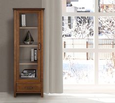 a wooden book shelf sitting next to a window with snow on the ground and trees outside