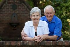 an older couple leaning on a brick wall